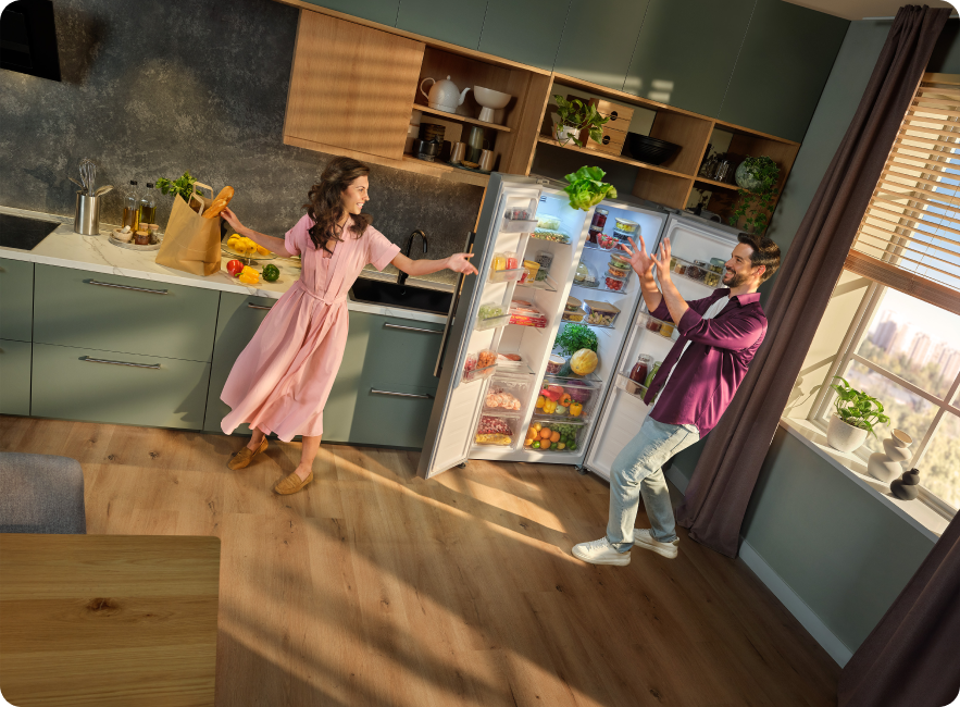 cuplu adaugand legume in frigider