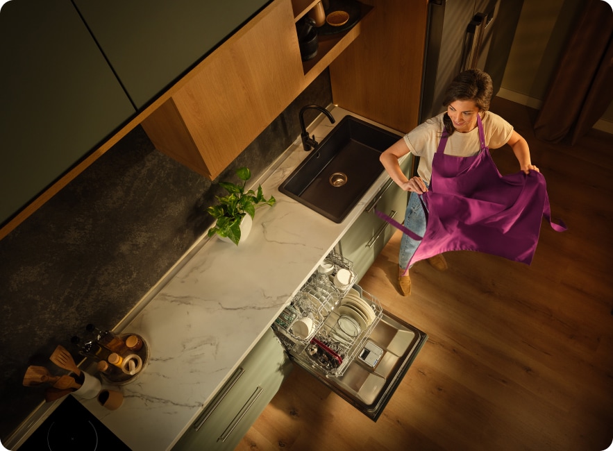 femeie scotand sortul alaturi de masina de spalat vase